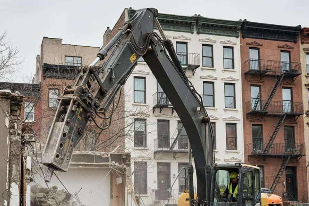 Excavator breaking concrete on a garage demolition site